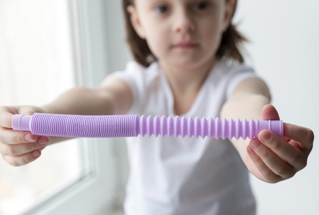 Predškolák naťahuje fialovú Pop trubicu oboma rukami
