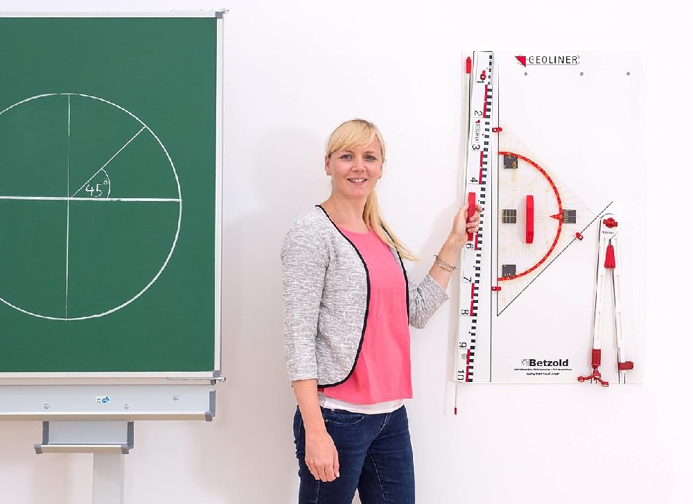 Učiteľka demonštruje rysovacie potreby na tabuľu počas hodiny geometrie v školskej učebni.