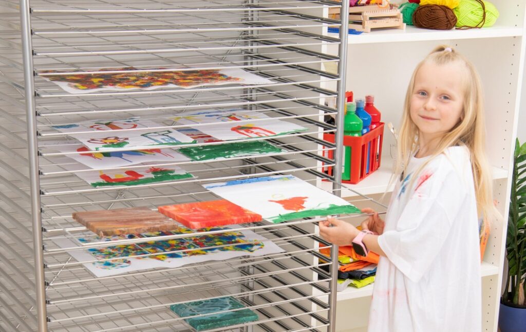 Dieťa vkladá výkres na vysúvateľnú policu stojana na výkresy pre školy.
