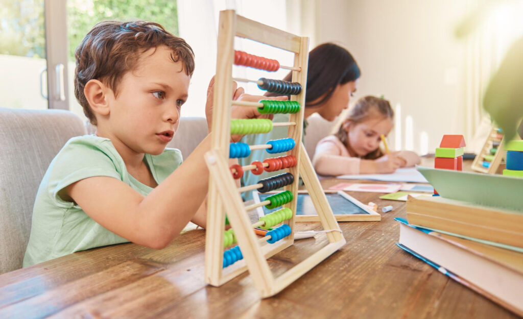 Dieťa používa drevené počítadlo pri učení matematiky doma. Počítadlo pre deti podporuje logické myslenie a prvé počítanie.